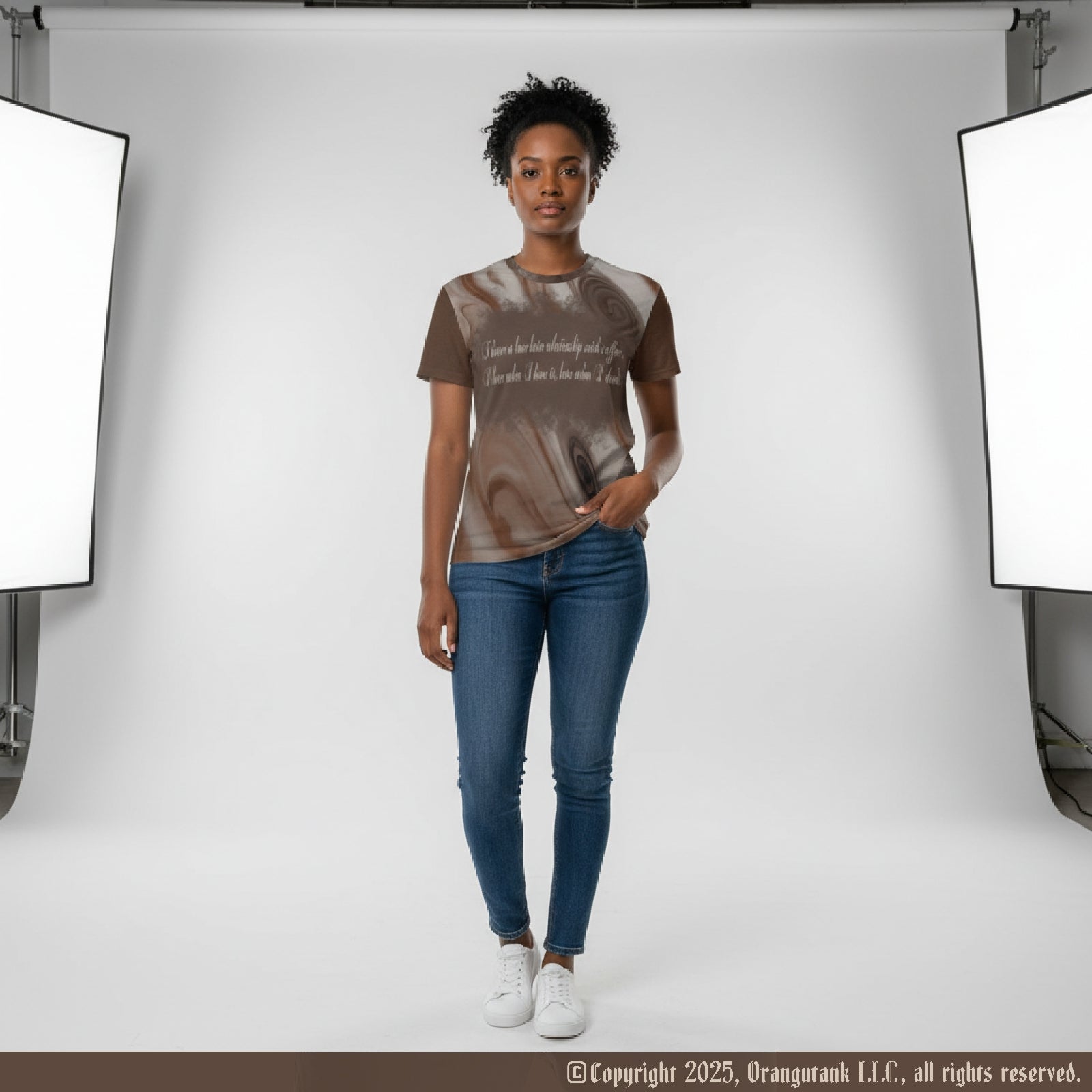 Female model wearing a brown and beige coffee pattern shirt with blue jeans standing in a studio setting with lighting equipment.